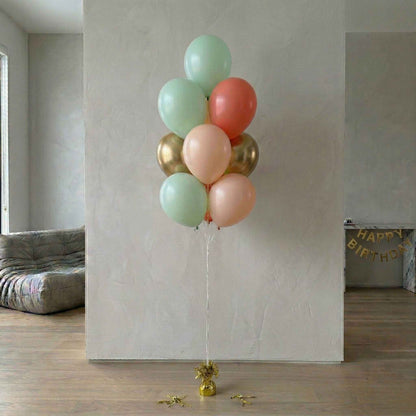 Bouquet of colorful balloons against a plain wall with 'Happy Birthday' banner in the background.