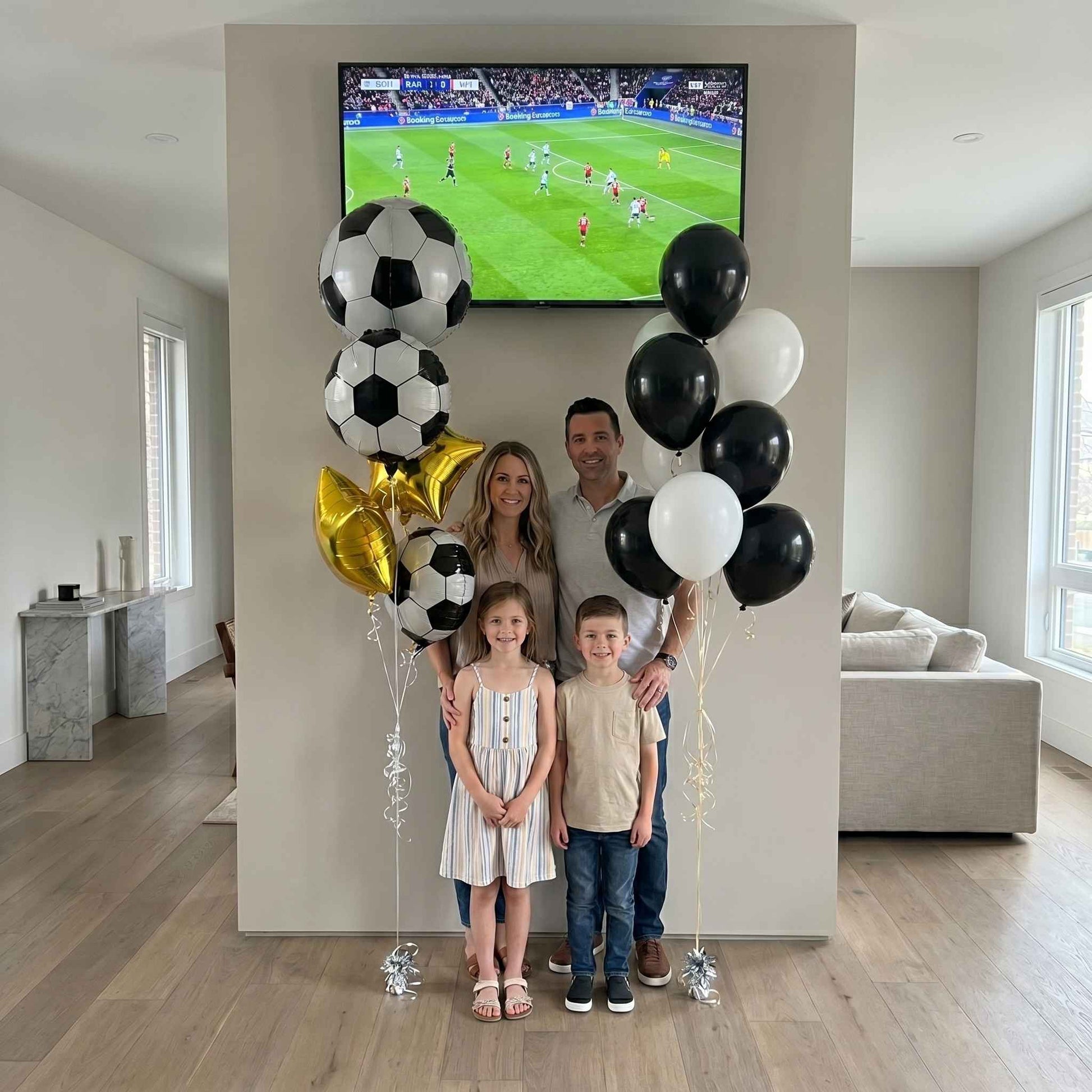 Family with soccer-themed balloons in a living room watching a soccer match on TV.