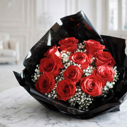 Bouquet of red roses with black wrap on a marble surface