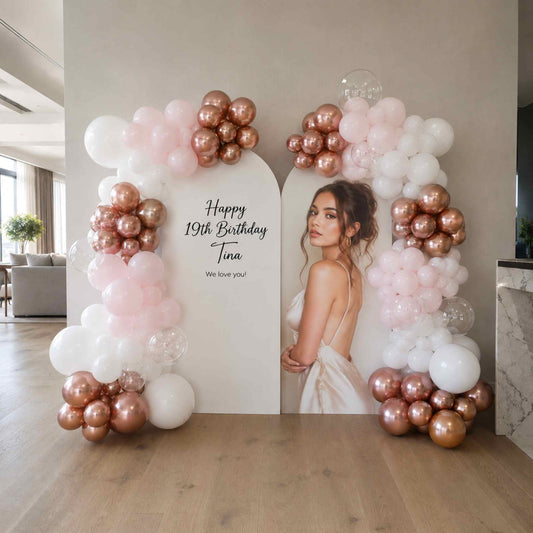 Woman posing in front of a balloon arch with 'Happy 19th Birthday Tina' text in a modern living room.