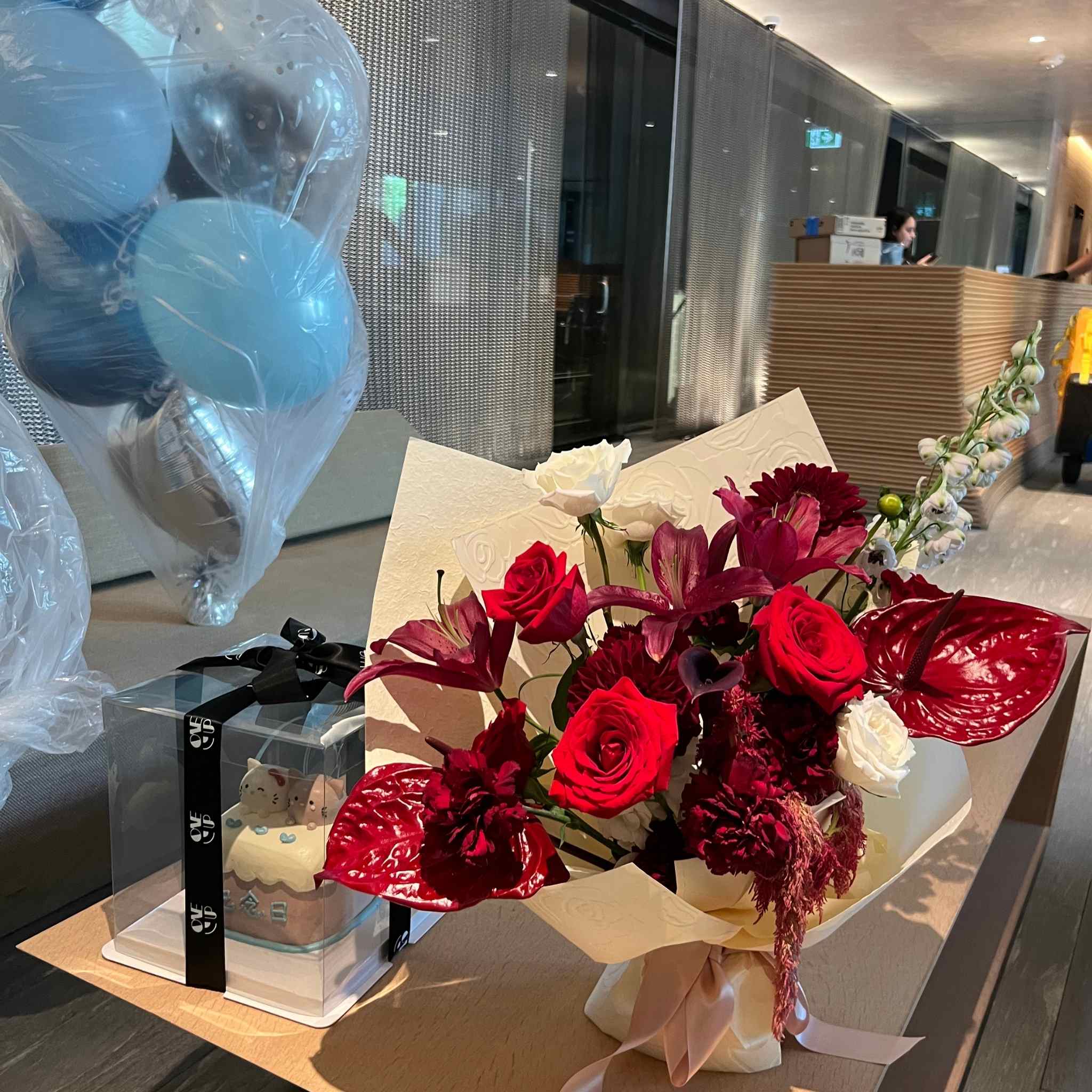 Bouquet of red and white flowers with balloons on a table.