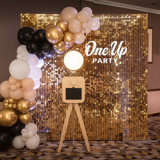Decorative setup with balloons and a 'One Up Party' backdrop