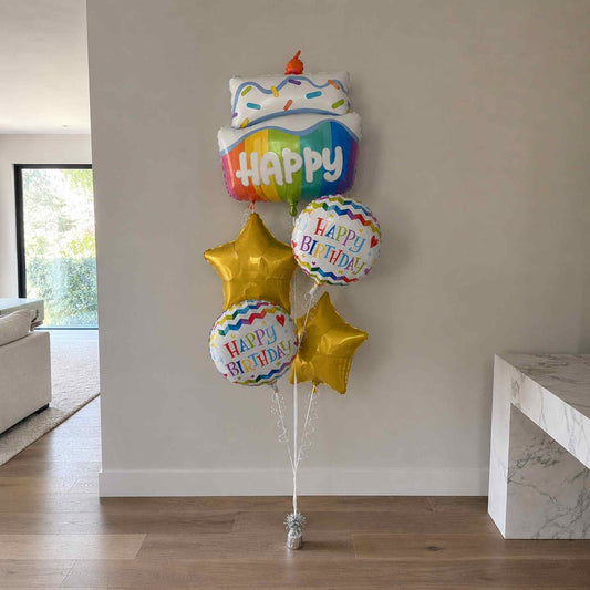 Colorful birthday balloons with 'Happy Birthday' text in a living room setting.