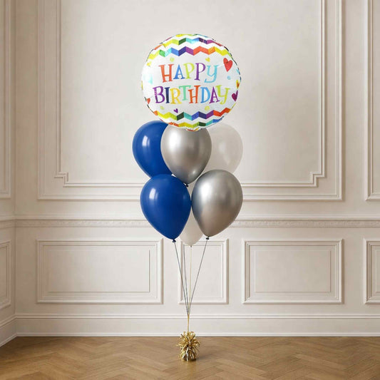Bouquet of balloons with a 'Happy Birthday' balloon against a white paneled wall.
