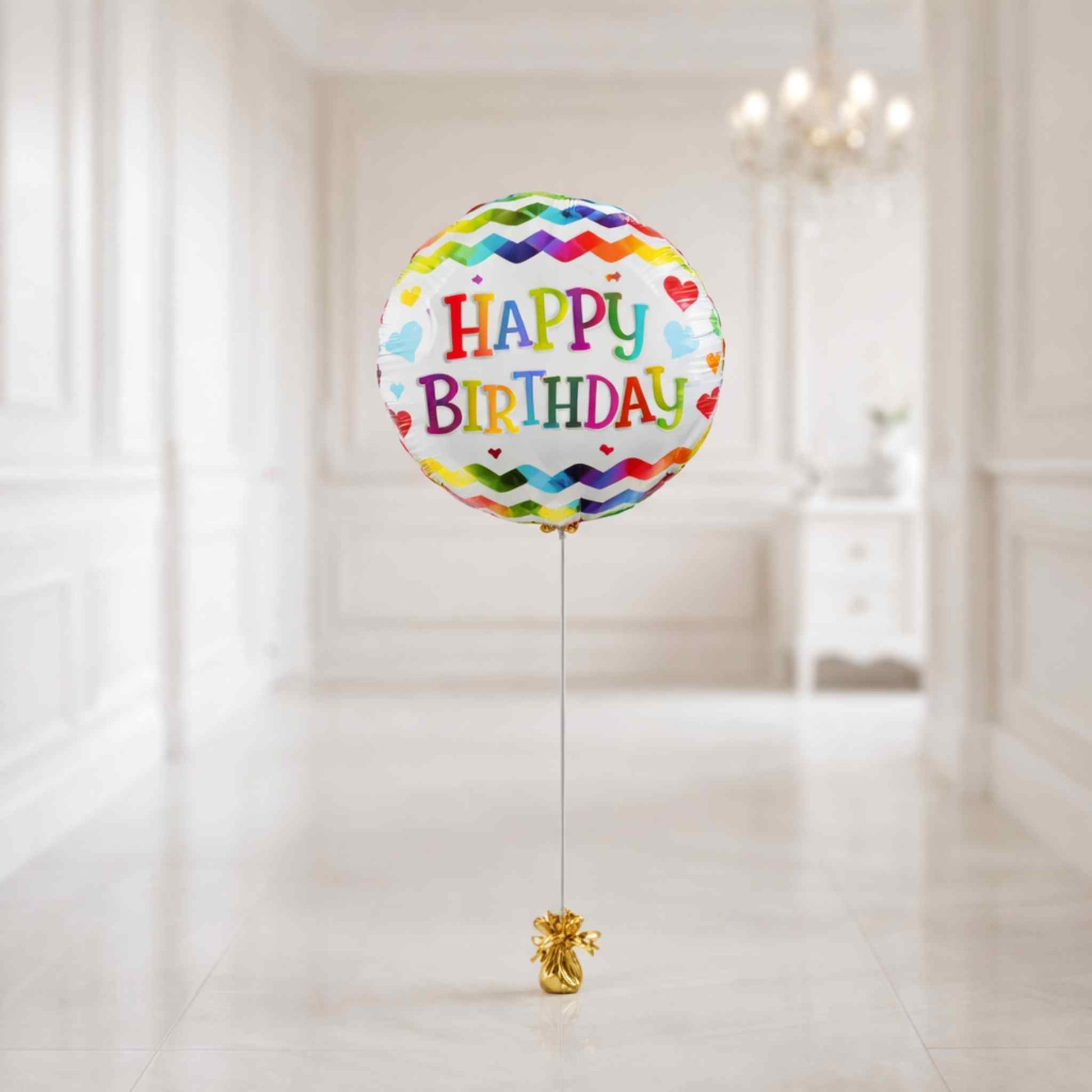 Colorful 'Happy Birthday' balloon with a gold ribbon on a white background