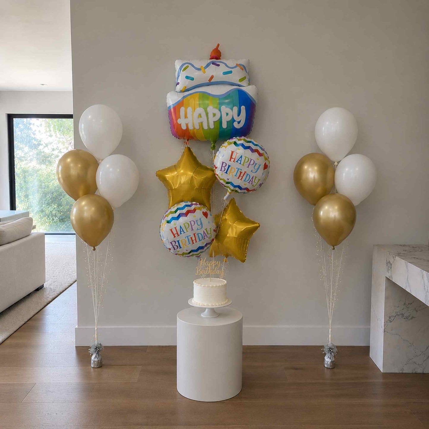 Colorful birthday balloons with a cake-shaped balloon and 'Happy Birthday' text in a living room.