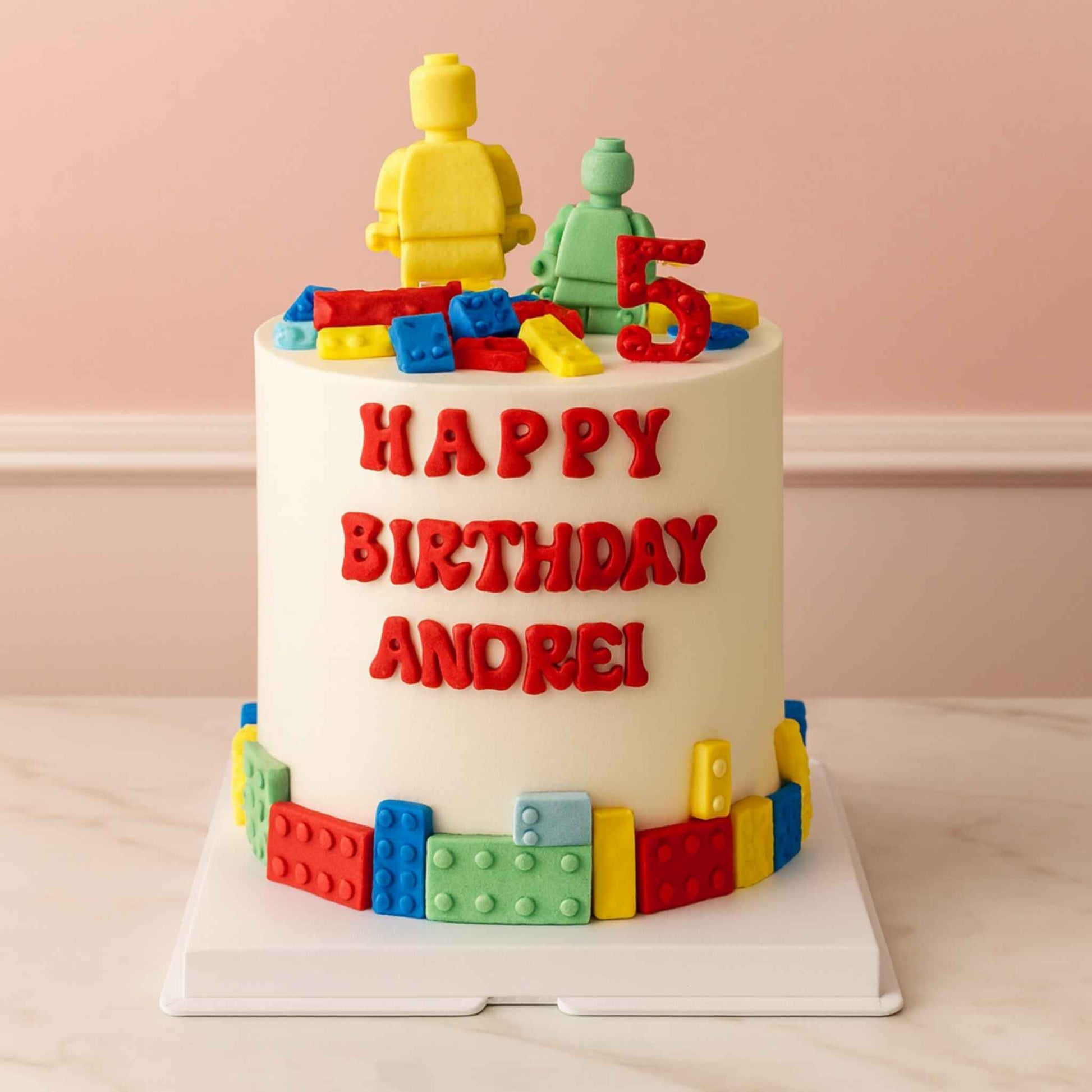 Birthday cake with colorful lego-themed decorations and 'Happy Birthday Andrei!' text on a light pink background.