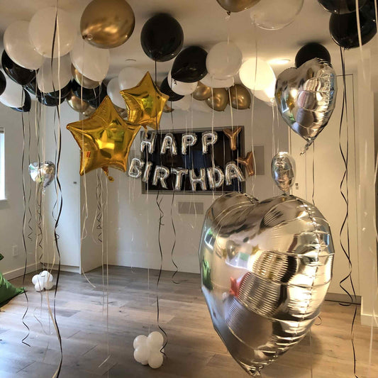 Birthday balloons including stars, numbers, and a 'Happy Birthday' banner in a room.