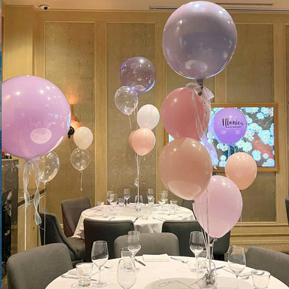 Decorated room with balloons and table settings, featuring a screen in the background.