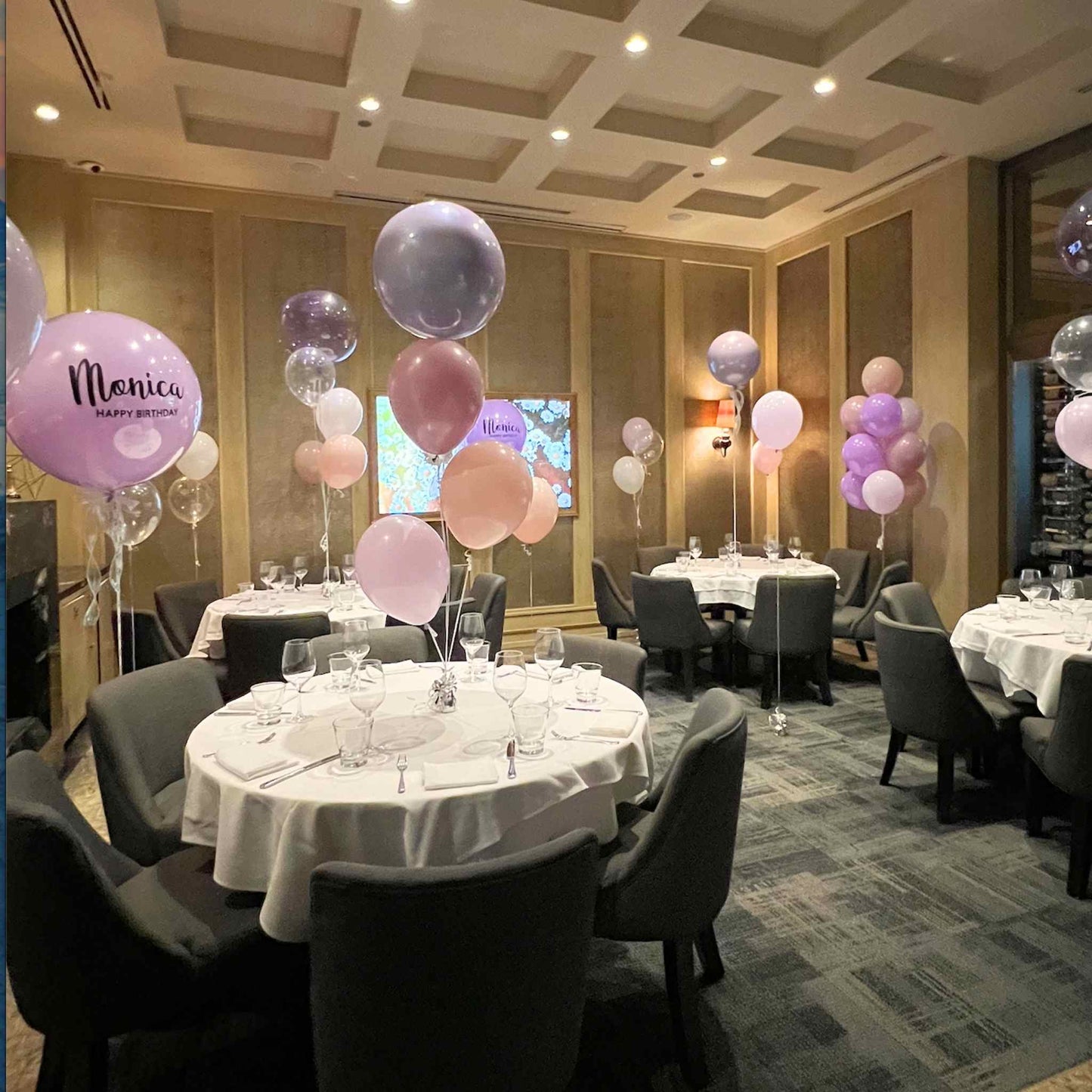 Decorated event room with tables, chairs, and balloons in a formal setting.