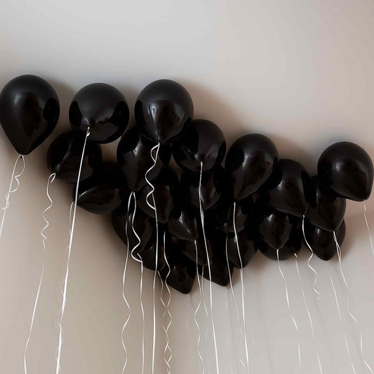 Black balloons with strings tied to a white wall