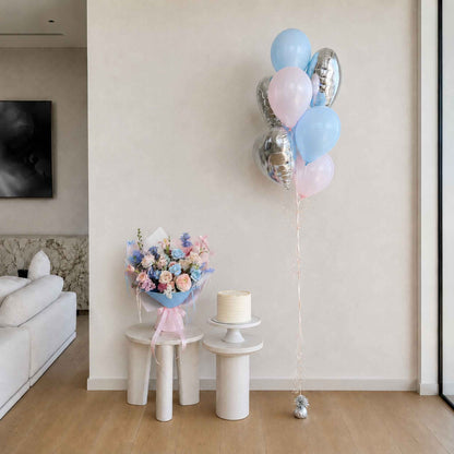 Decorative balloons, flowers, and cake on small tables in a room.