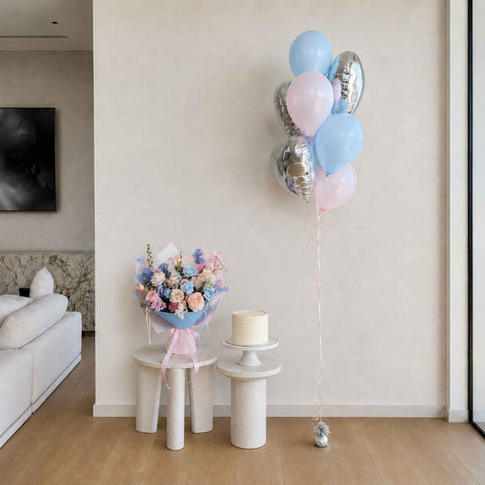 Decorative balloons, flowers, and cake on small tables in a room.