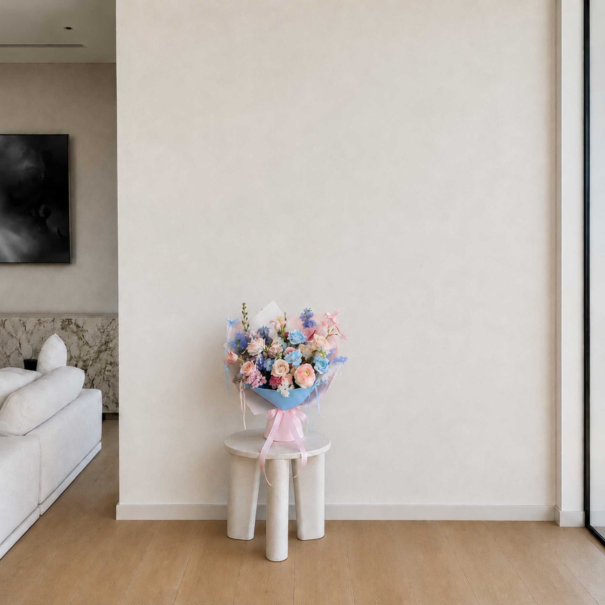 Bouquet of flowers on a small white stool against a plain wall in a modern living room.