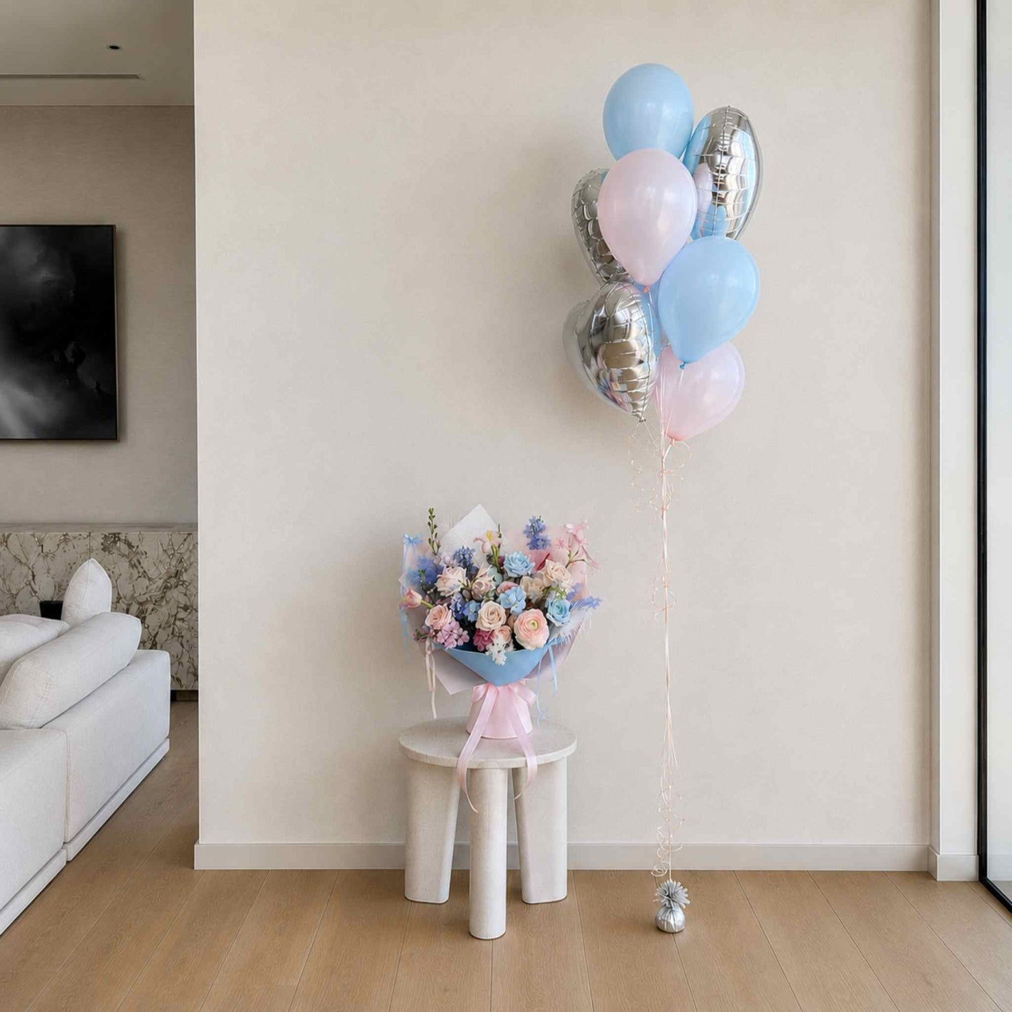 Bouquet of flowers on a small table with balloons in a room.