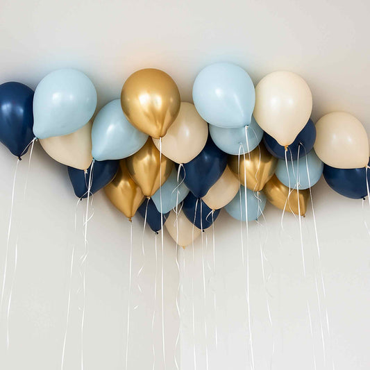 Balloons in blue, gold, and beige colors arranged in a decorative pattern against a white background.