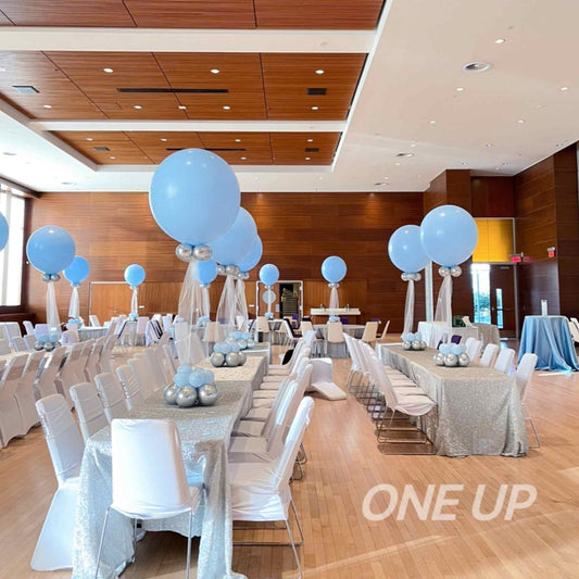Decorated event space with tables, chairs, and blue balloons in a large room.