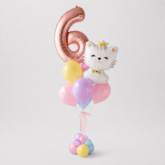 A birthday balloon bouquet featuring a large metallic rose-gold foil balloon shaped like the number 6, a white cartoon cat balloon with a gold crown and bow tie, and several pastel latex balloons in pink, purple, yellow, and blue, set against a light gray studio background.