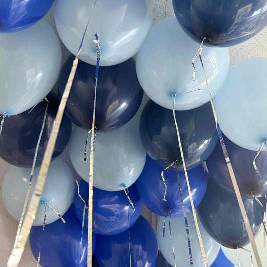 Blue and white balloons with ribbons against a neutral background