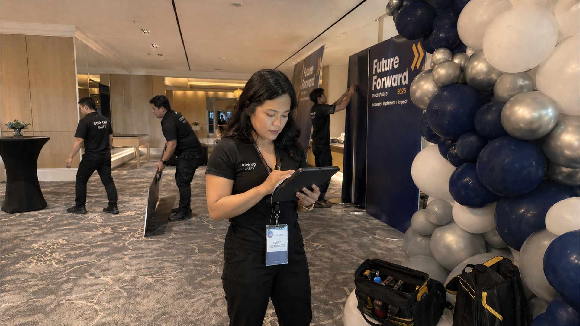 Person using a tablet in a conference room with balloons and event setup.