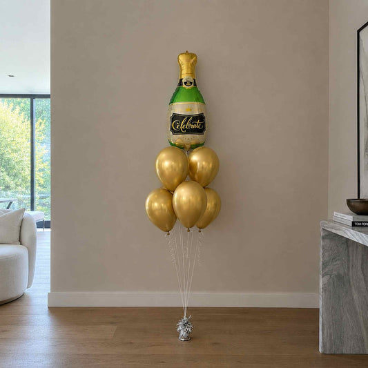 Gold champagne bottle balloon decoration against a beige wall in a living room.