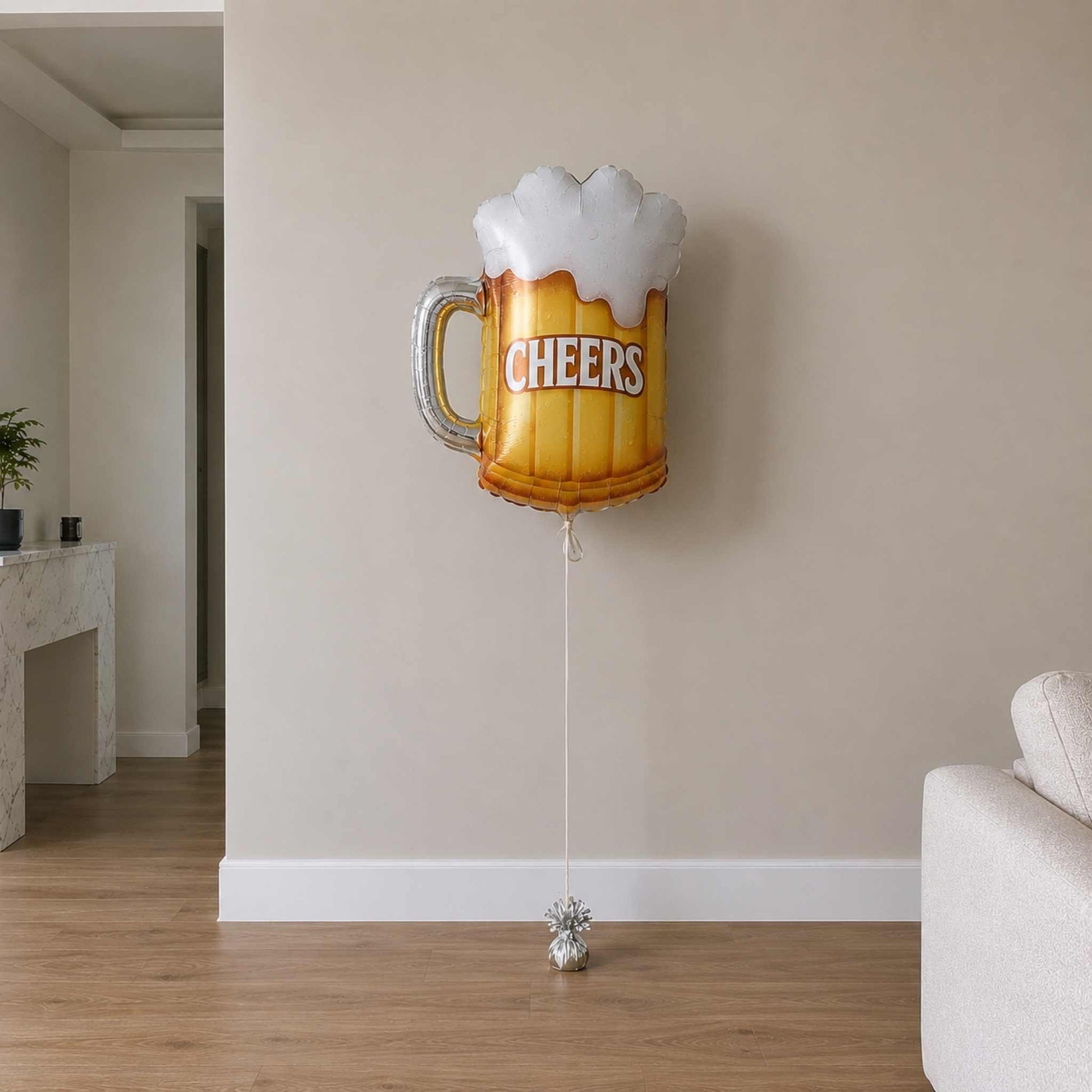 Beer mug balloon with 'Cheers' text in a room with a couch and plant.