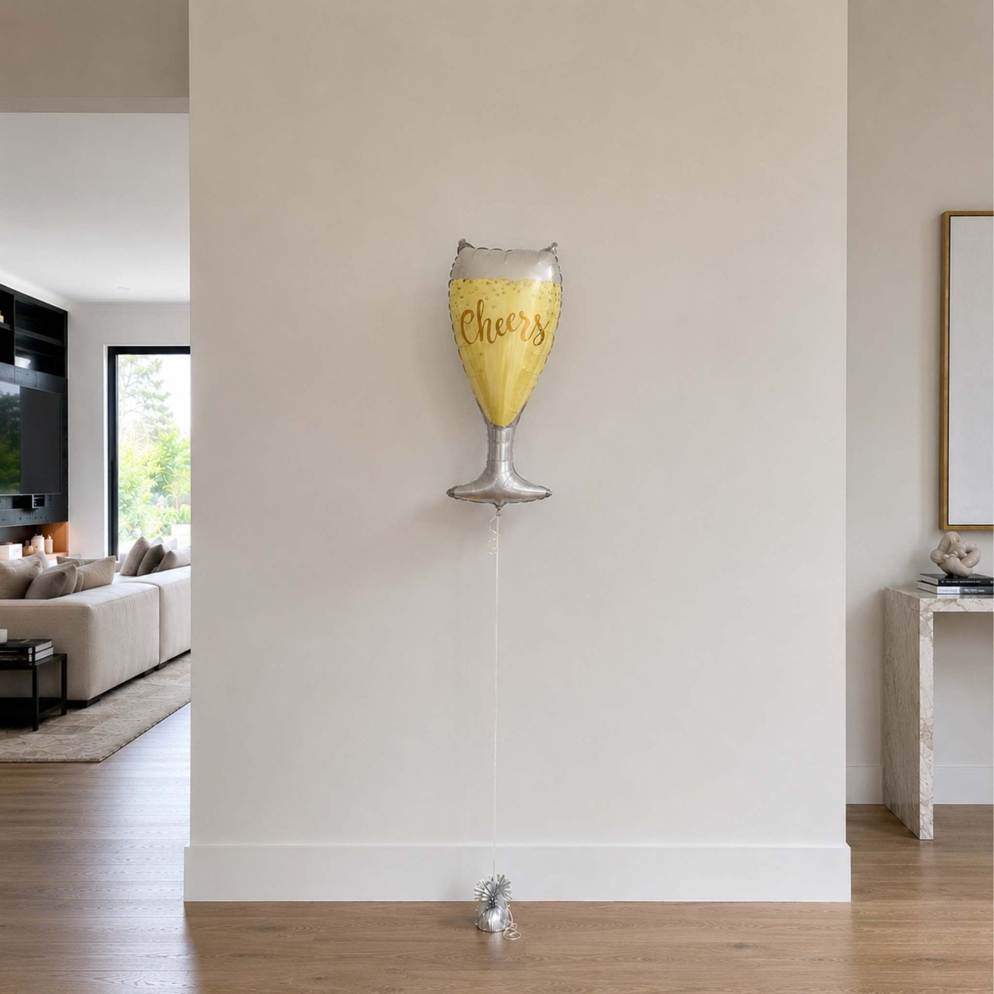 Decorative balloon shaped like a champagne glass with 'Cheers' text in a living room setting.