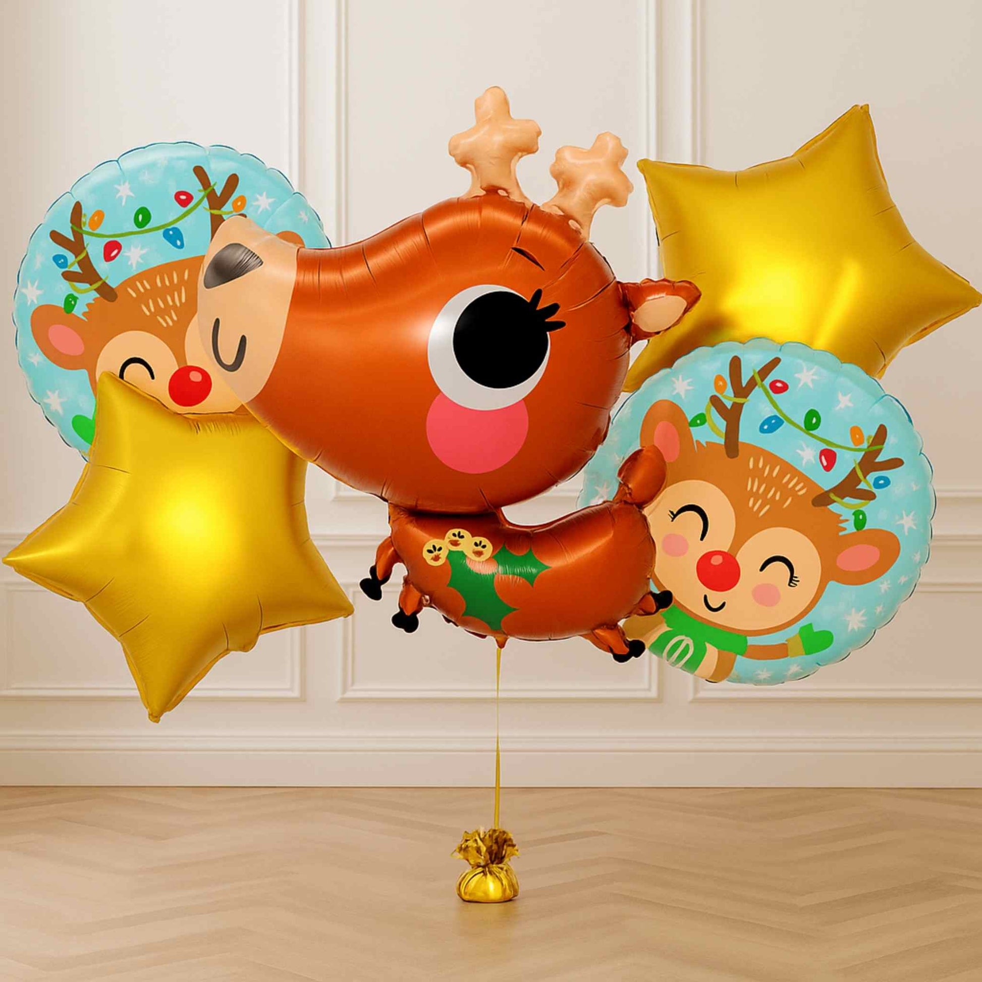 Decorative balloons shaped like reindeer with gold stars on a wooden floor.