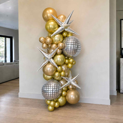 Decorative arrangement of gold, silver, and mirror ball balloons against a neutral wall.