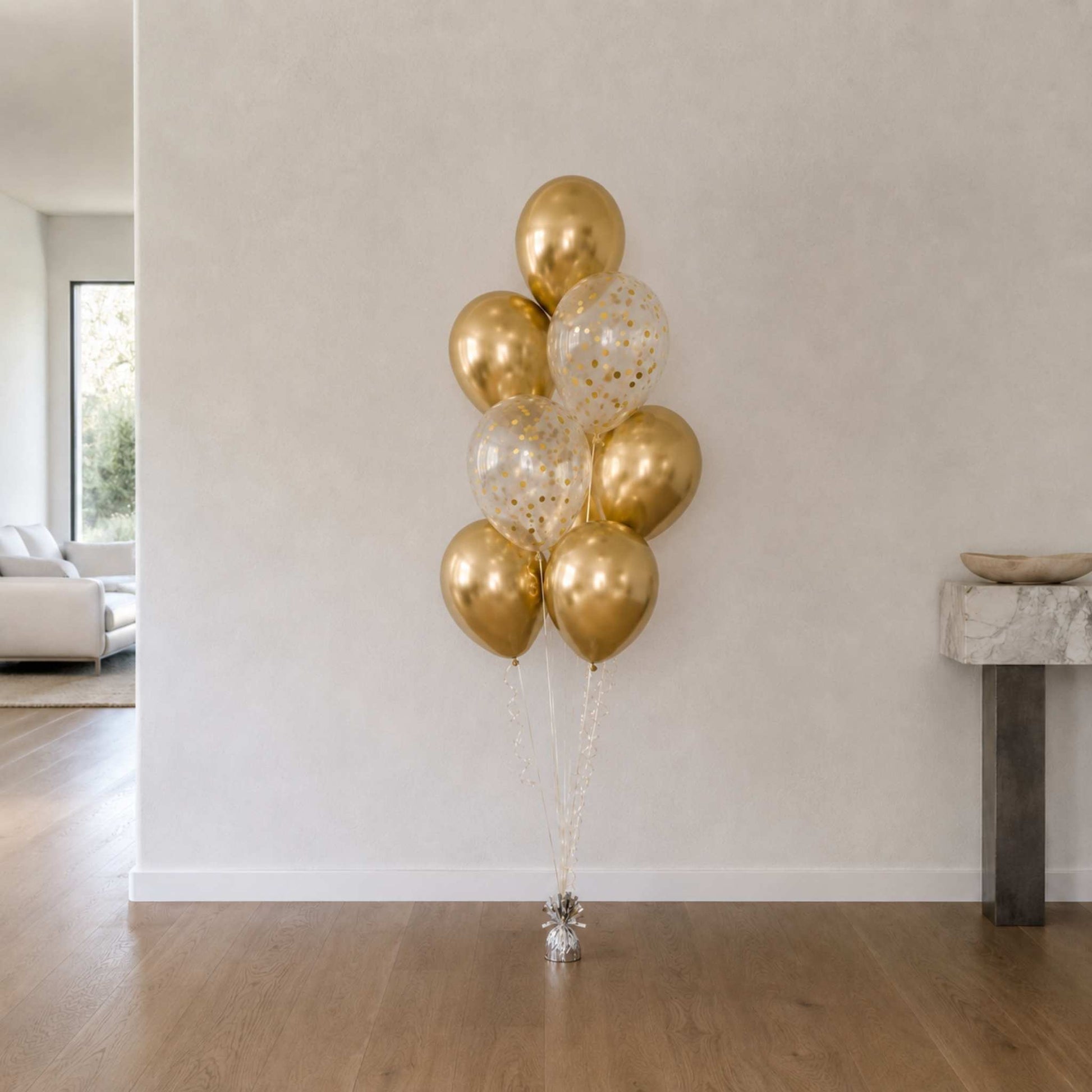 Bouquet of gold and clear balloons in a minimalistic room.