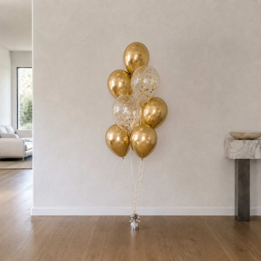 Bouquet of gold and clear balloons in a minimalistic room.