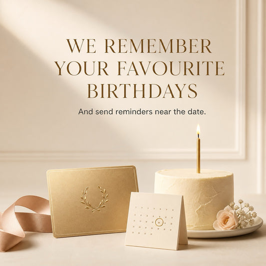 A styled birthday remembrance scene with a cream cake, a single lit candle, a small card, and a gold card on a light surface. Large text reads, 'WE REMEMBER YOUR FAVOURITE BIRTHDAYS And send reminders near the date.