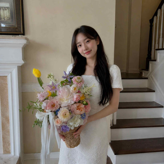 Woman in a white dress holding a bouquet of flowers indoors.