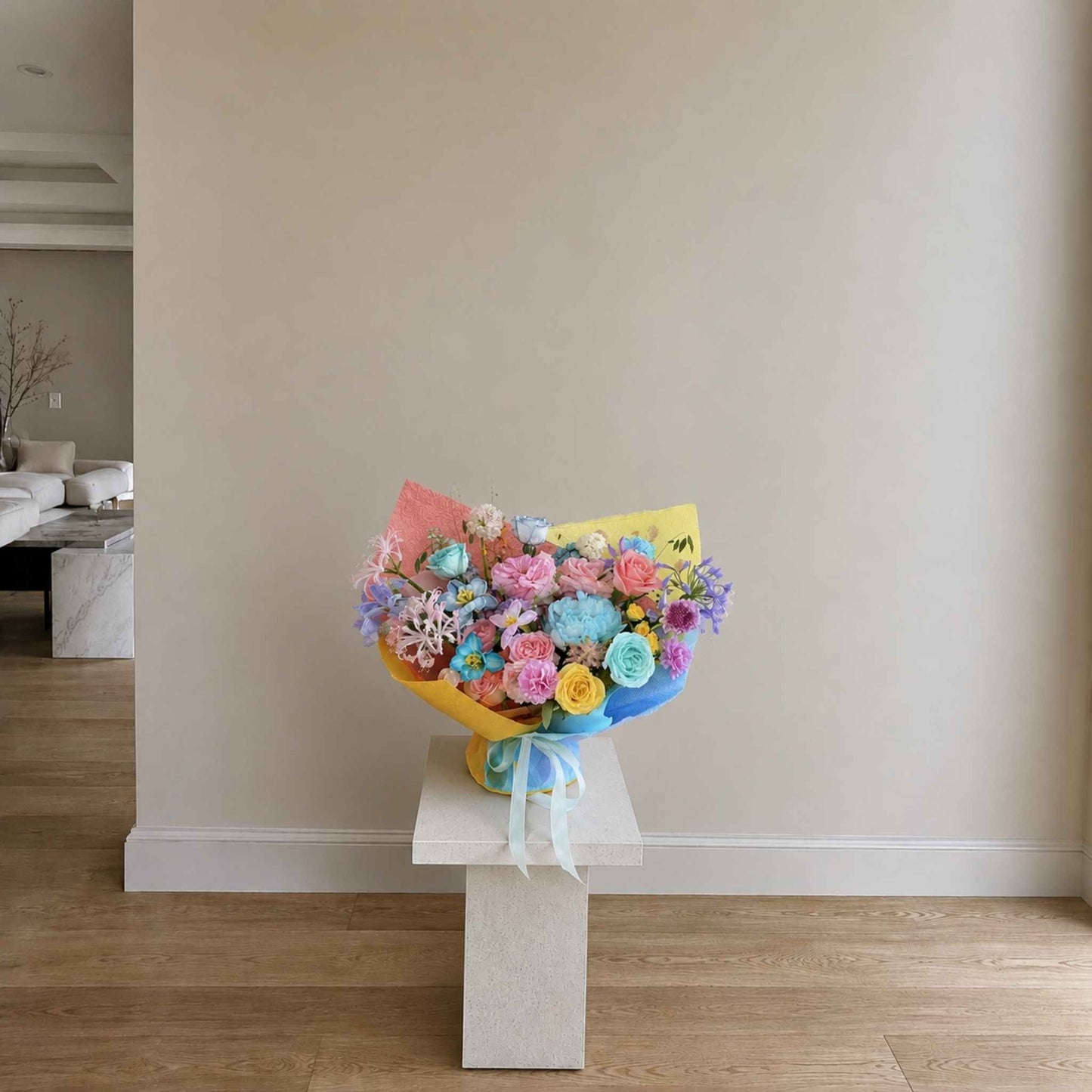 Colorful bouquet of flowers on a white pedestal against a neutral wall.