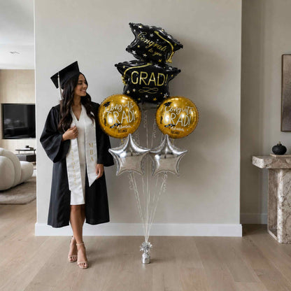 Graduate in cap and gown holding balloons in a home setting