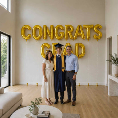 Graduate with family in front of 'CONGRATS GRAD' balloons in a modern living room.
