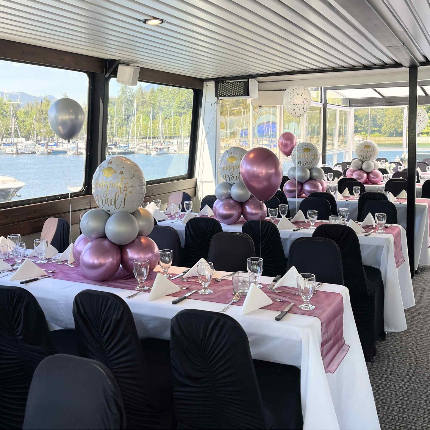 Decorated boat interior with tables set for a event, balloons, and chairs.