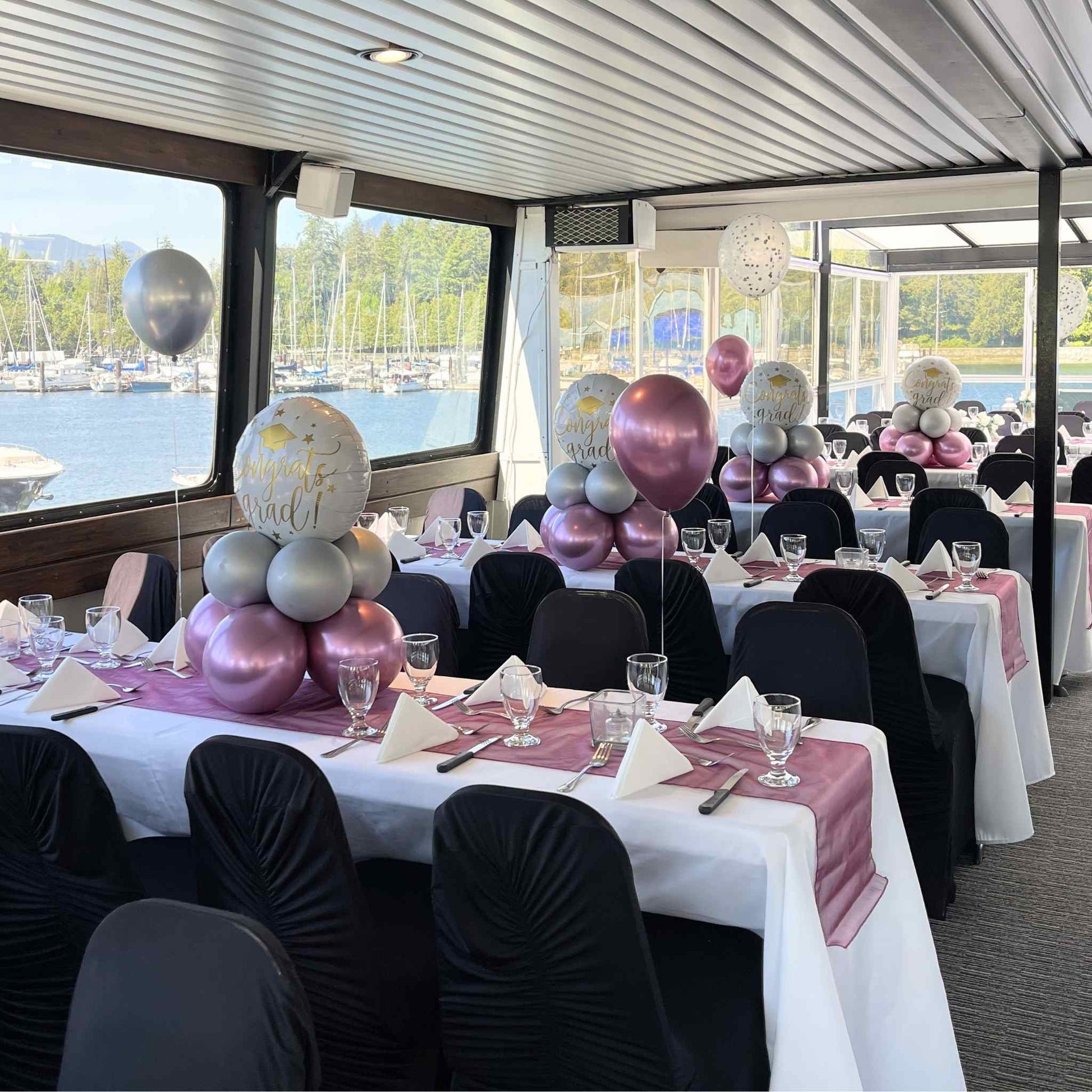 Decorated boat interior with tables set for a event, balloons, and chairs.