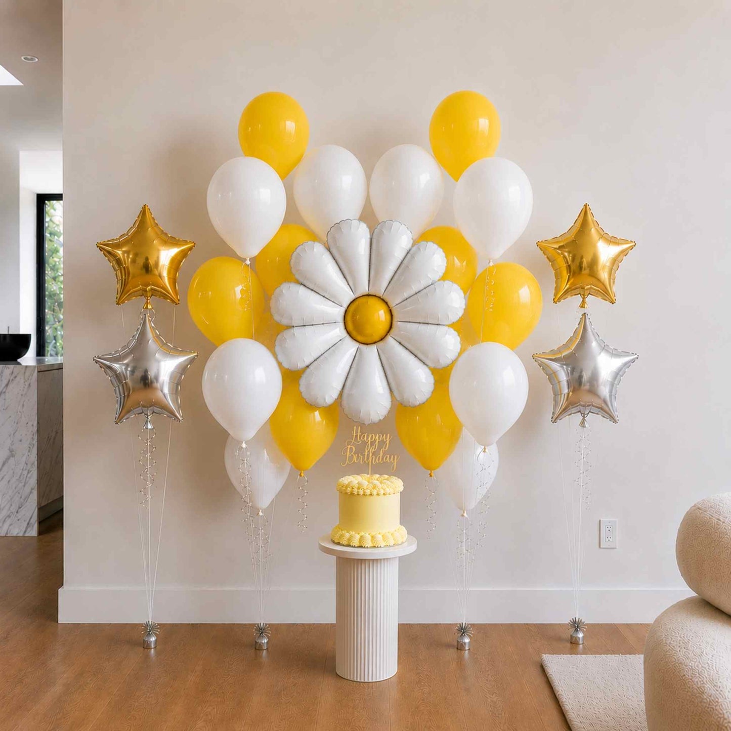 Decorative balloon arrangement with yellow, white, and gold balloons, a cake, and 'Happy Birthday' text on a stand.