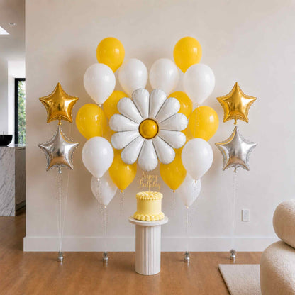 Decorative balloon arrangement with yellow, white, and gold balloons, a cake, and 'Happy Birthday' text on a stand.