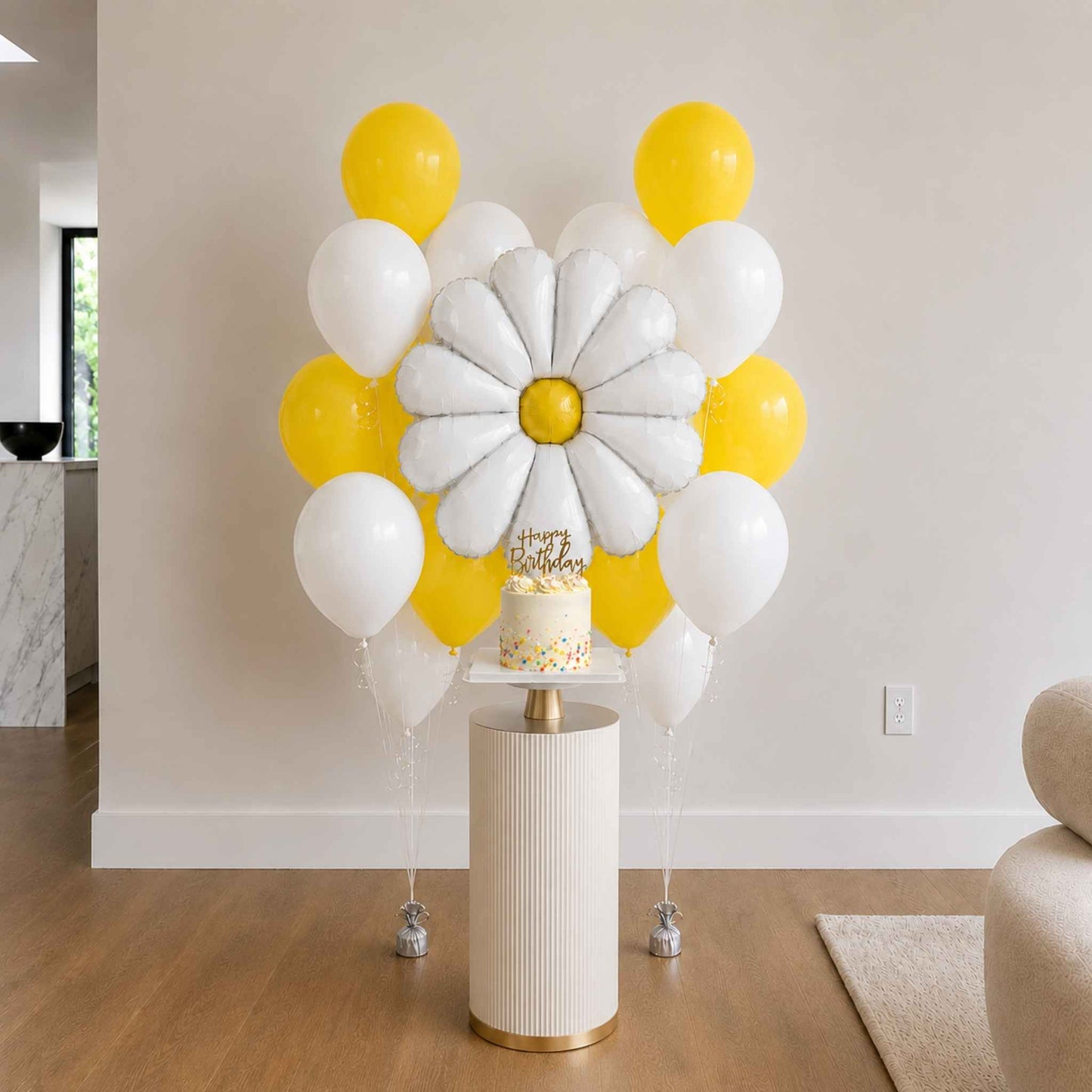 Decorative balloon arch with a cake on a pedestal in a room setting.
