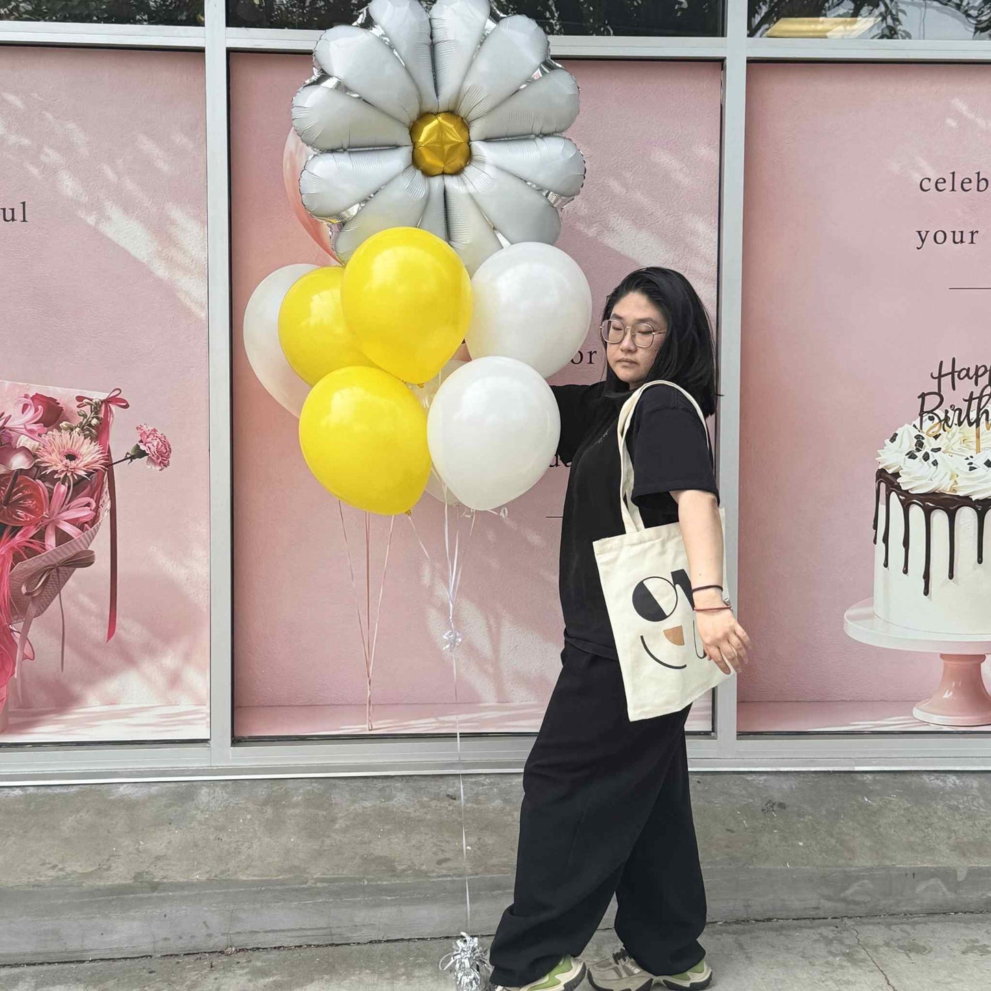 Person holding balloons in front of a store window with festive decorations.