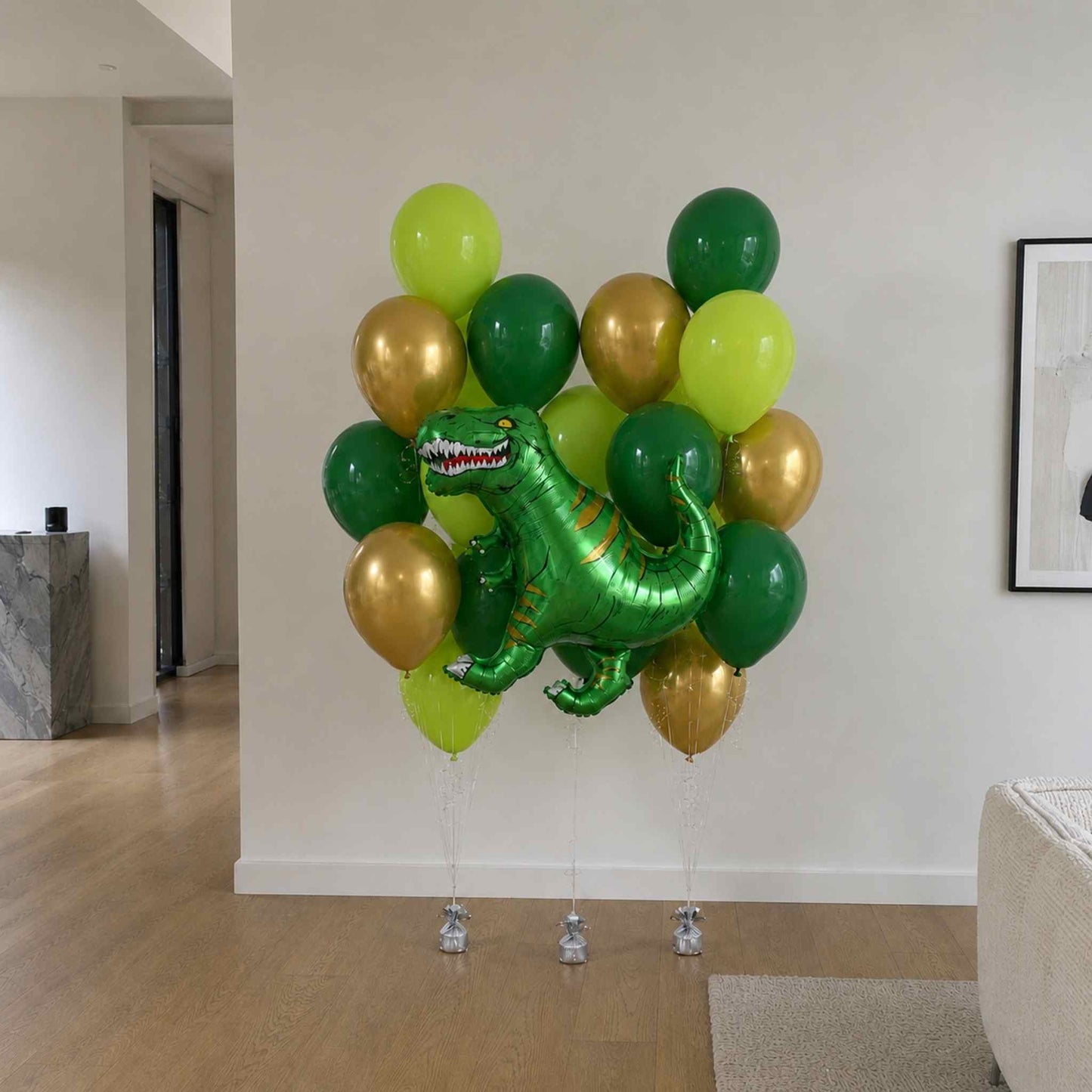 Bunch of green, gold, and silver balloons with a dinosaur design in a room.