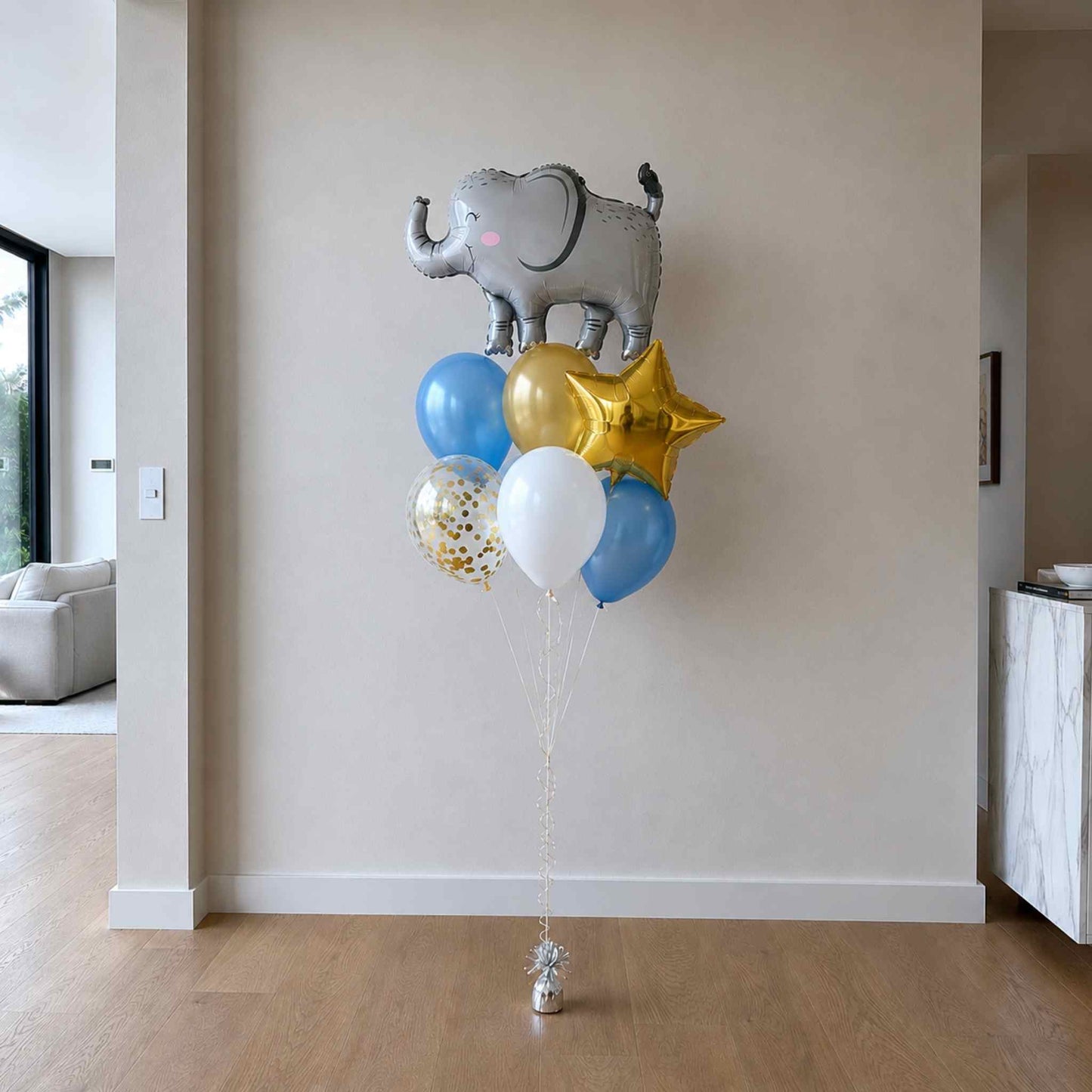 Balloon bouquet with elephant, stars, and colorful balloons in a room.