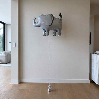 Gray elephant-shaped balloon on a wall in a room with wooden flooring.