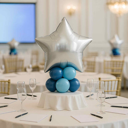 Decorative balloon arrangement on a table with a silver star balloon in a banquet hall.