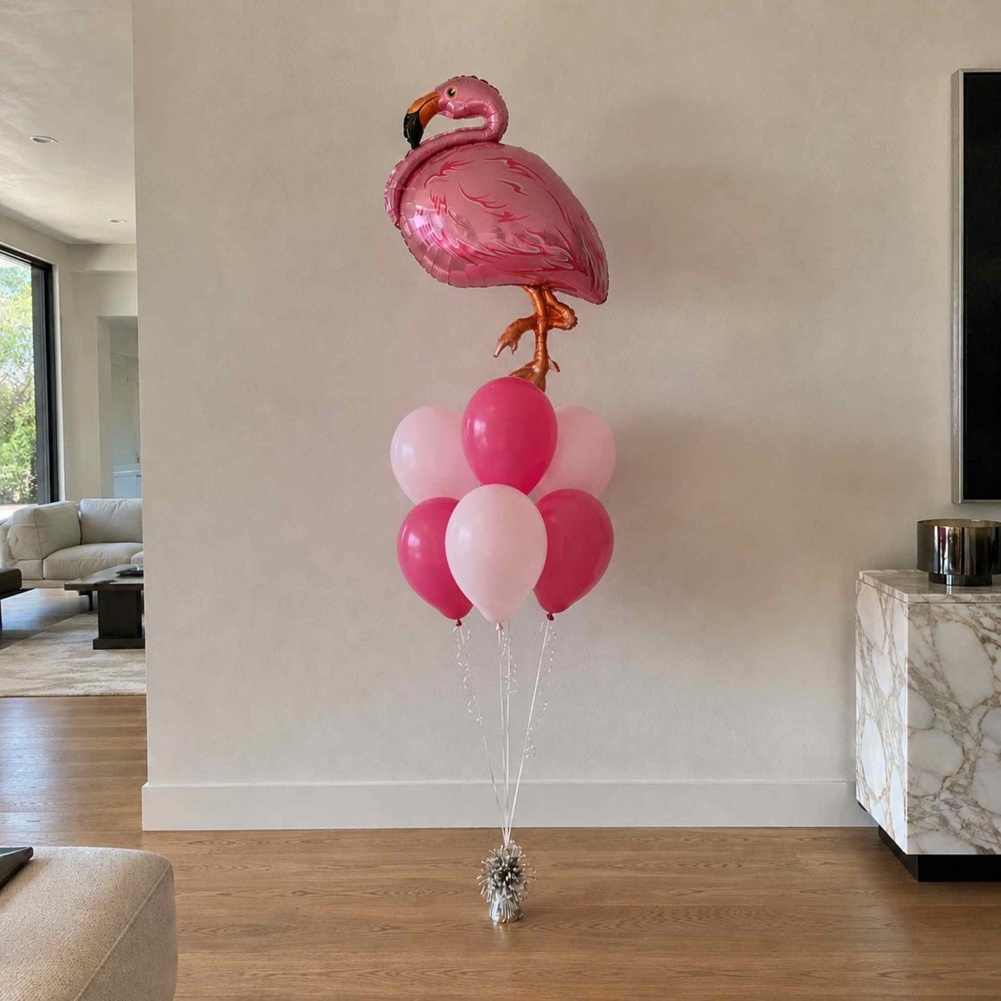 Flamingo-shaped balloon with pink and white balloons in a living room setting