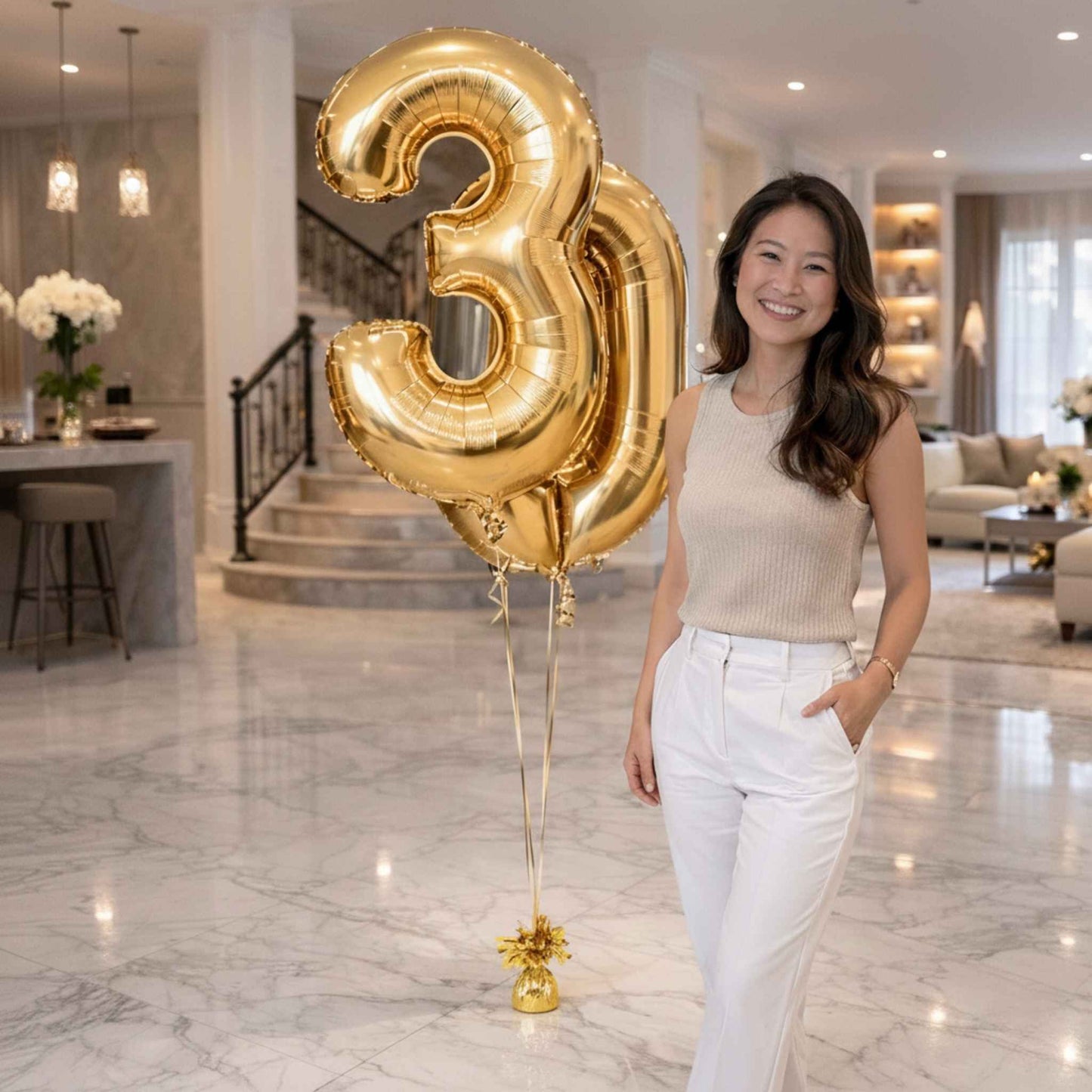Woman standing by gold number 3 and 0 balloons in a luxurious home setting