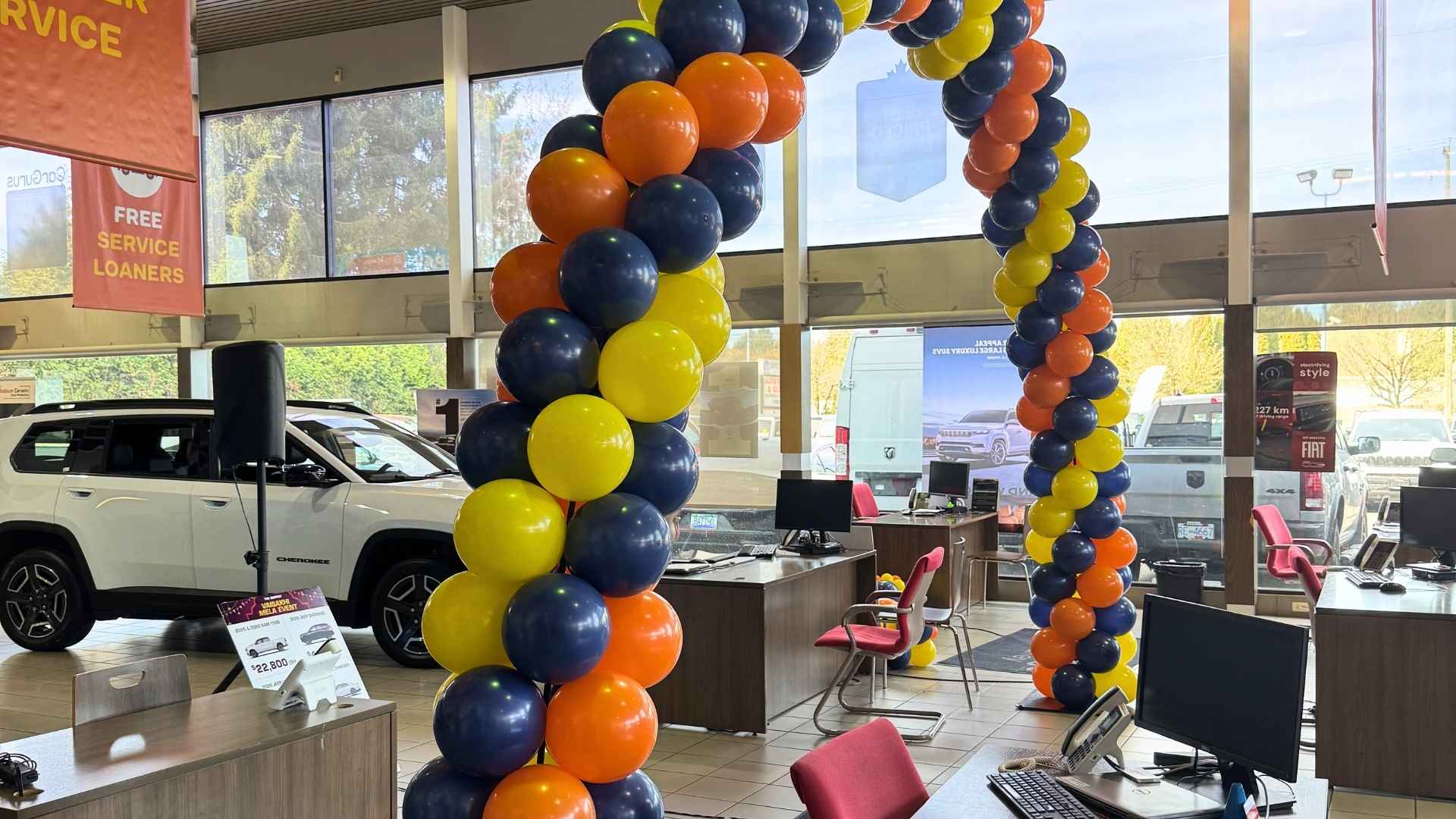 Decorative balloon arch in a car dealership with desks and computers.