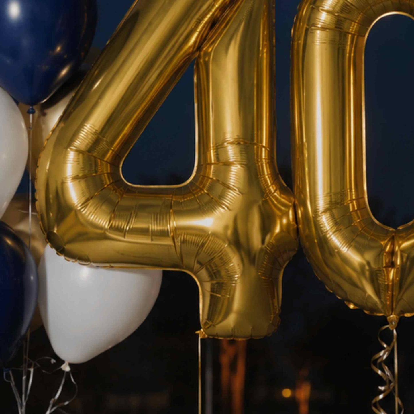 Gold metallic foil balloons forming the numbers 4 and 0, with partial navy and white balloons in the background.